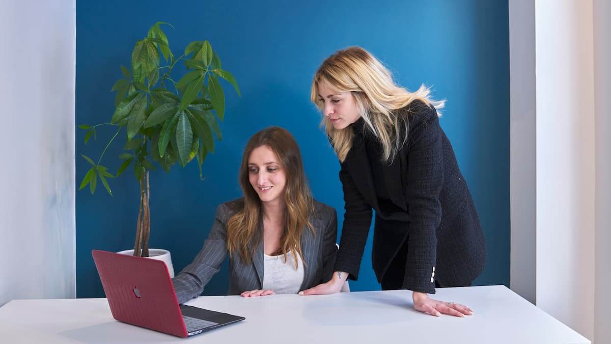 Deux femmes regardent un ordinateur portable dans un bureau.